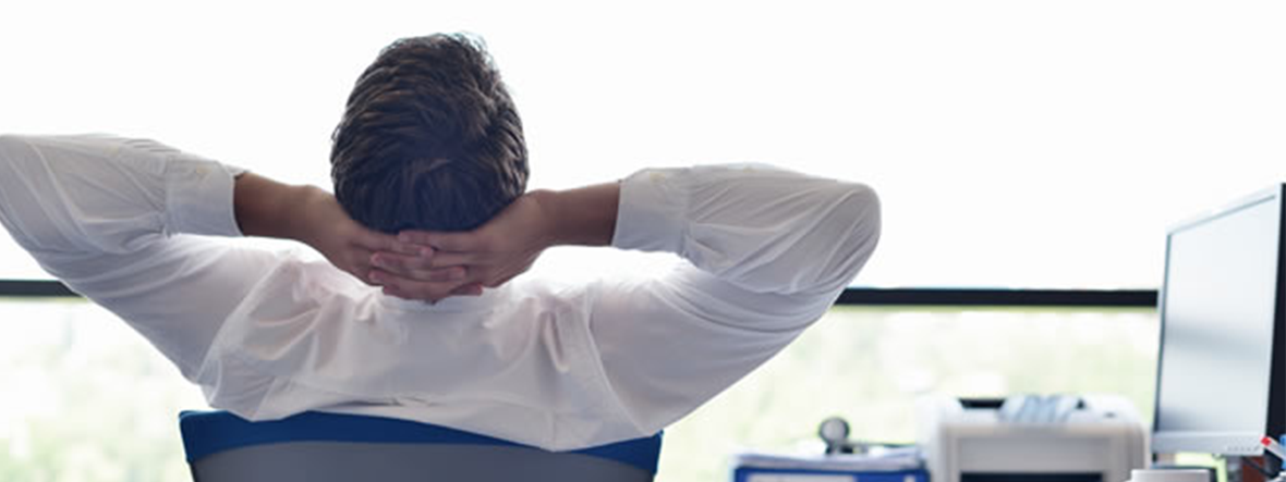 a man leaning back from his working desk